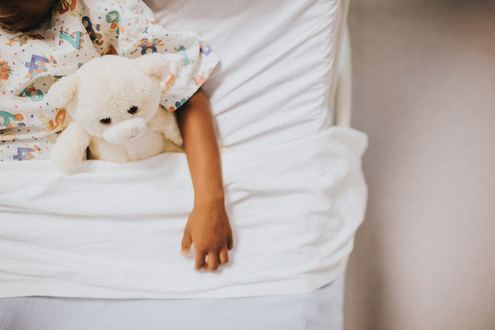 Picture of young child in bed with a teddy bear.  Displaying Parent Coach, Life Coach, Mentor.  